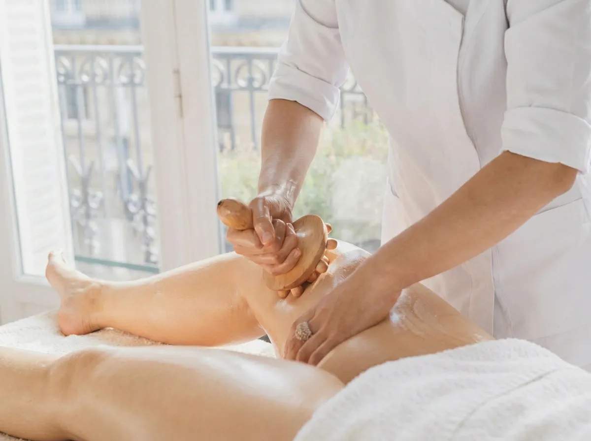 Femme allongée recevant un massage madérothérapie avec un rouleau en bois sur la cuisse